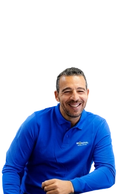 Portrait détendu et souriant d’un collaborateur Mondial Pare-Brise en polo bleu, incarnant la proximité et la bonne humeur au sein du réseau.
