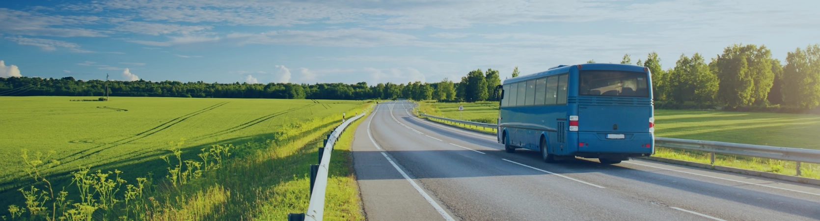 Bus roulant sur une route de campagne entourée de verdure sous un ciel dégagé, symbole de mobilité sereine et de trajets en toute sécurité.