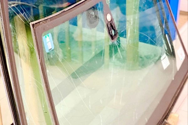 Pare-brise fissuré en attente de remplacement, mis en évidence dans un atelier technique. Les impacts visibles montrent l’importance d’intervenir rapidement pour garantir la sécurité du conducteur.