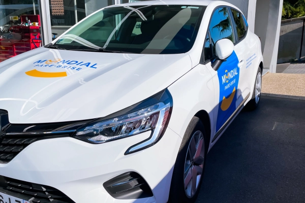 Véhicule de service Mondial Pare-Brise stationné devant un centre, prêt à intervenir pour vos besoins en vitrage automobile.