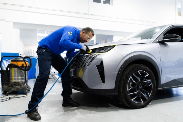 Technicien Mondial Pare-Brise polissant un feux de voiture suite au changement de la vitre du phare.