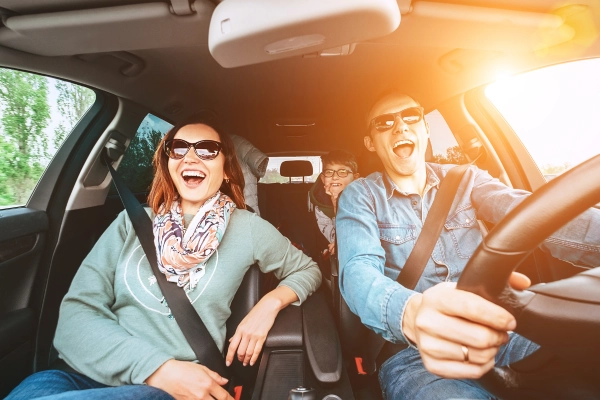 Famille souriante en voiture, profitant d’un trajet en toute sérénité, symbole de sécurité et de plaisir de conduire.