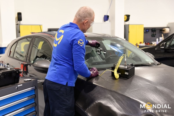 Technicien réparant un impact sur le pare-brise