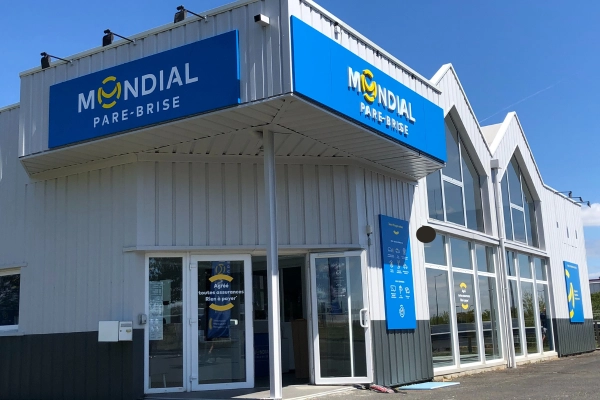 Façade d’un centre Mondial Pare-Brise moderne avec enseigne bien visible, sous un ciel bleu, incarnant professionnalisme et proximité.
