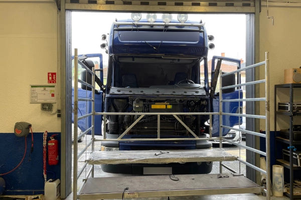 Poids lourd en cours d’intervention technique dans un atelier Mondial Pare-Brise, avec échafaudage en place pour une opération sécurisée sur le pare-brise.